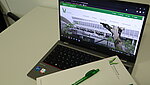 geöffneter Laptop mit der Startseite der PH Ludwigsburg. Auf der Laptop-Tastatur liegen ein Block und ein Kugelschreiber aus dem PH Merchandisingsortiment