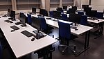 Blick auf Tische mit Bildschirmen und blauen Stühlen im PC-Raum der PHL.