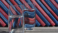 Gläser mit Wassser gefüllt vor Bücherregal