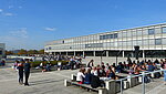 Blick auf Hauptgebäude, Studierende an Tischen vor PH