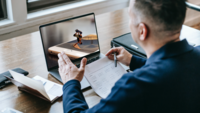 Mann vor Laptop, auf dem Bildschirm ist ein Skateboardfahrer