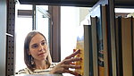 Studentin durchforstet Bücher in einem Bücherregal der Bibliothek der PH Ludwigsburg.