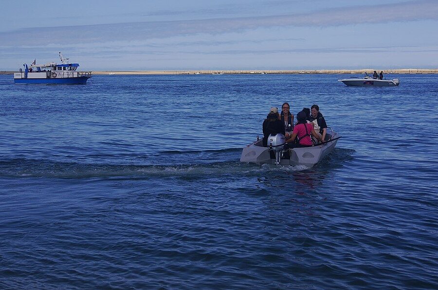 Mit kleinen Beibooten geht es weiter auf die Sandbank. In Hintergrund ist das Forschungsboot "Planula 4" des CNRS-INSU zu sehen.