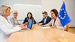 Picture of people sitting at a desk with the European flag 