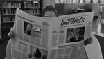 Eine Person liest Zeitung in der Bibliothek der PH.